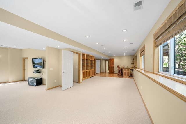 below grade area featuring light carpet, recessed lighting, and baseboards