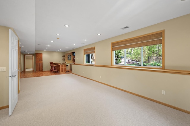 unfurnished living room featuring light colored carpet, recessed lighting, baseboards, and bar