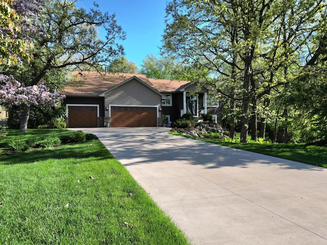 view of front facade with a garage, a front lawn, concrete driveway, and stone siding