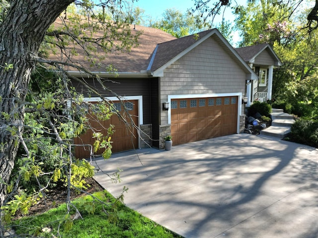 view of home's exterior featuring driveway, roof with shingles, a garage, and stone siding