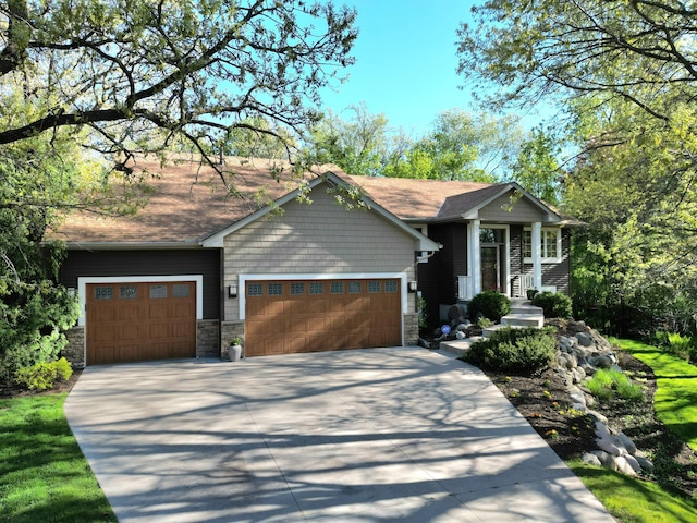 view of front of house featuring stone siding, a garage, and driveway