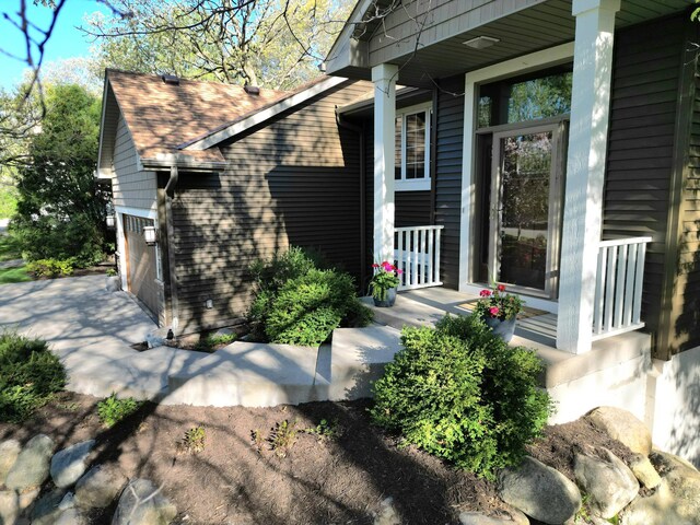 doorway to property featuring roof with shingles and a porch