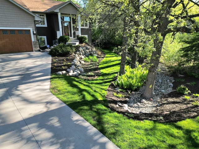 view of front of property with driveway, stone siding, a garage, and a front yard