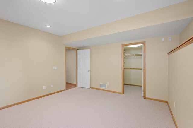 unfurnished bedroom with baseboards, recessed lighting, carpet, a spacious closet, and a closet