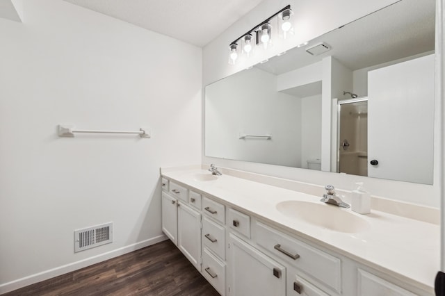 10911 Rhode Island Ave S, Bloomington, MN 55438 - bathroom with an enclosed shower, baseboards, wood finished floors, toilet, and double vanity