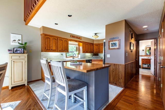 6385 13th Ave NW, Rochester, MN 55901 - kitchen with butcher block countertops, light wood-style flooring, brown cabinetry, a breakfast bar, and a textured ceiling