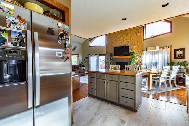 6385 13th Ave NW, Rochester, MN 55901 - kitchen with stainless steel fridge, gray cabinetry, open floor plan, wooden counters, and a large fireplace