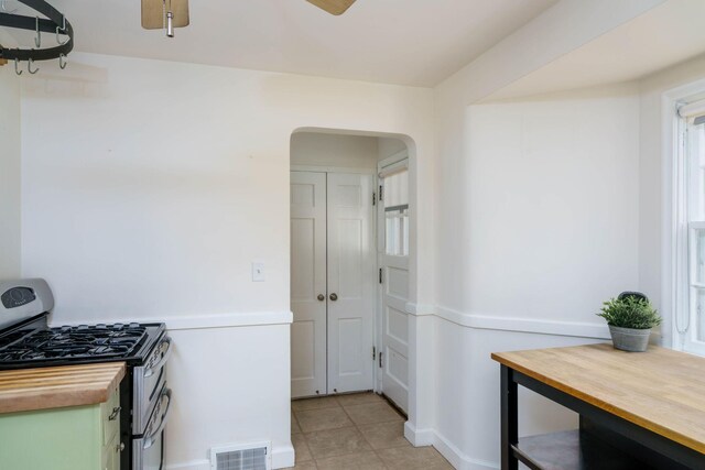 623 Fairview Ave S, Saint Paul, MN 55116 - kitchen featuring butcher block countertops, stainless steel range with gas cooktop, arched walkways, a ceiling fan, and light tile patterned flooring