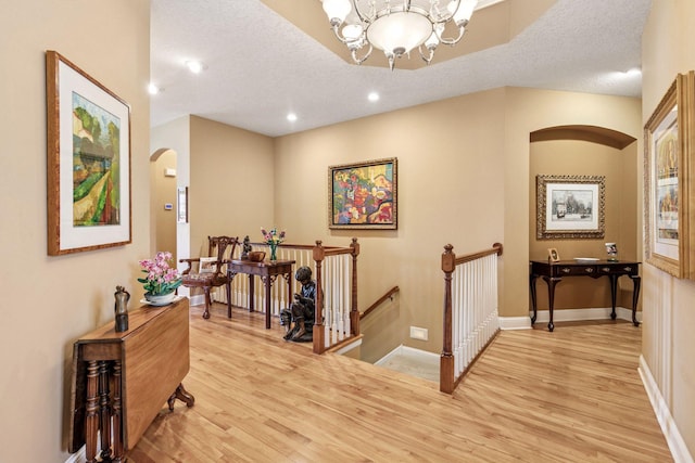 130 Stonebridge Rd, Lilydale, MN 55118 - hall featuring an upstairs landing, arched walkways, light wood-style floors, a textured ceiling, and a chandelier