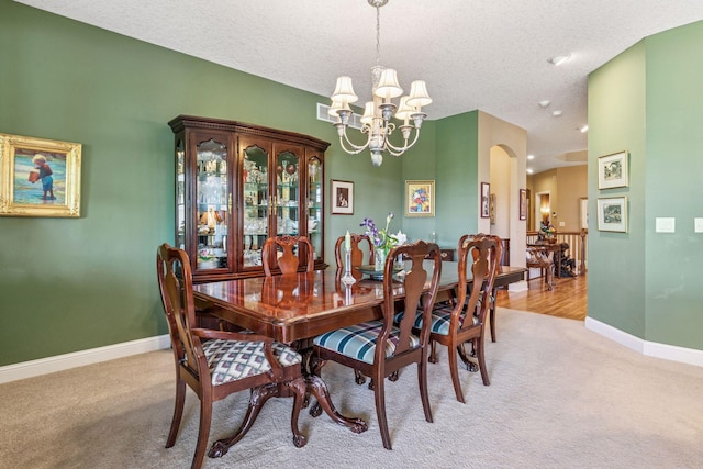 130 Stonebridge Rd, Lilydale, MN 55118 - dining area with light colored carpet, a chandelier, baseboards, arched walkways, and a textured ceiling