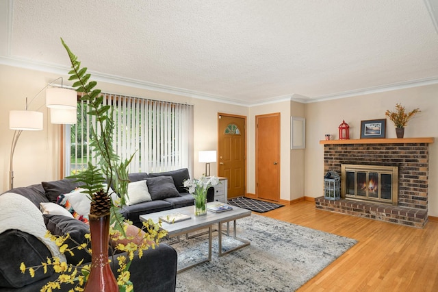 living room featuring a textured ceiling, wood finished floors, a fireplace, crown molding, and baseboards