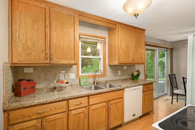 kitchen featuring a sink, white dishwasher, light wood finished floors, tasteful backsplash, and a textured ceiling