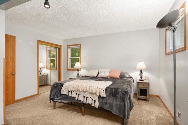 bedroom featuring light colored carpet, a closet, a textured ceiling, and baseboards