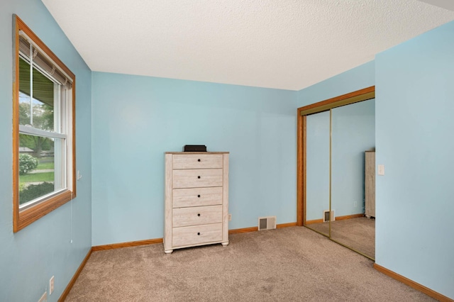 unfurnished bedroom with carpet floors, a closet, baseboards, and a textured ceiling