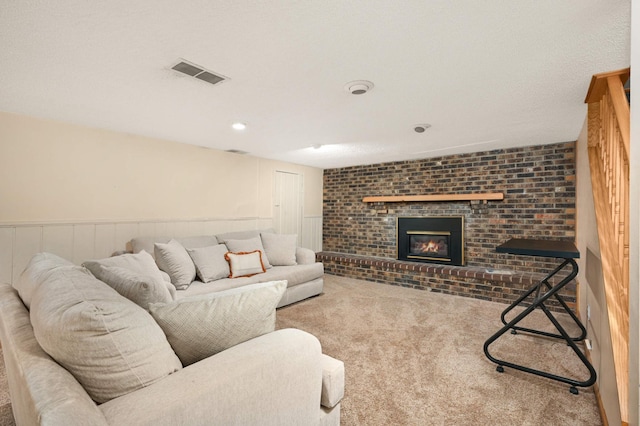 carpeted living room featuring a brick fireplace and wainscoting