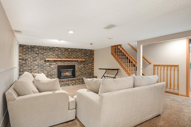 living room with light colored carpet, stairway, a textured ceiling, and a fireplace