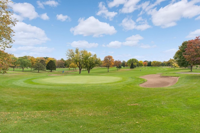 view of property's community featuring view of golf course and a yard