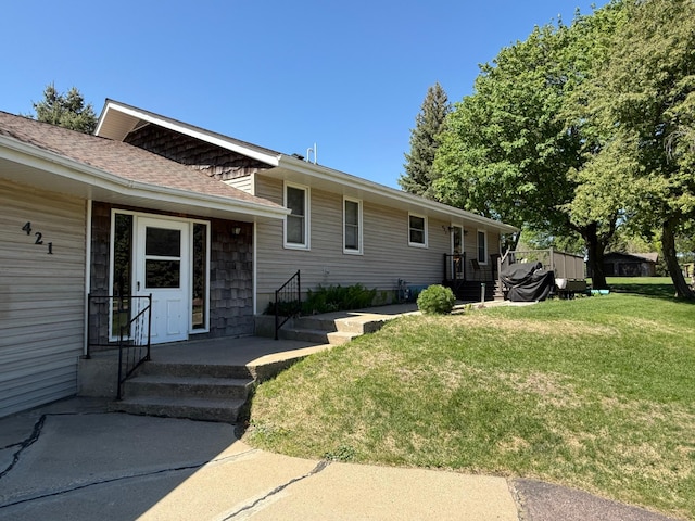 view of front of home with a front yard and a shingled roof