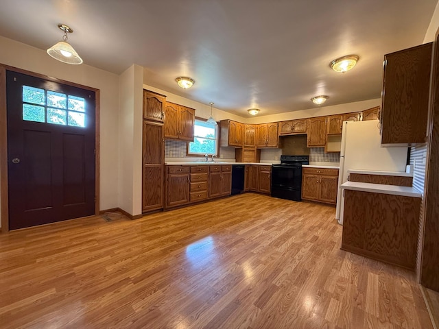 421 Oxford St W, Worthington, MN 56187 - kitchen featuring black appliances, brown cabinetry, a sink, light wood finished floors, and light countertops