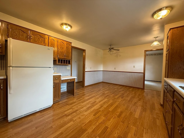 421 Oxford St W, Worthington, MN 56187 - kitchen featuring freestanding refrigerator, wood finished floors, ceiling fan, light countertops, and wainscoting