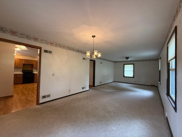 421 Oxford St W, Worthington, MN 56187 - unfurnished room featuring light colored carpet, ceiling fan, a chandelier, and baseboards