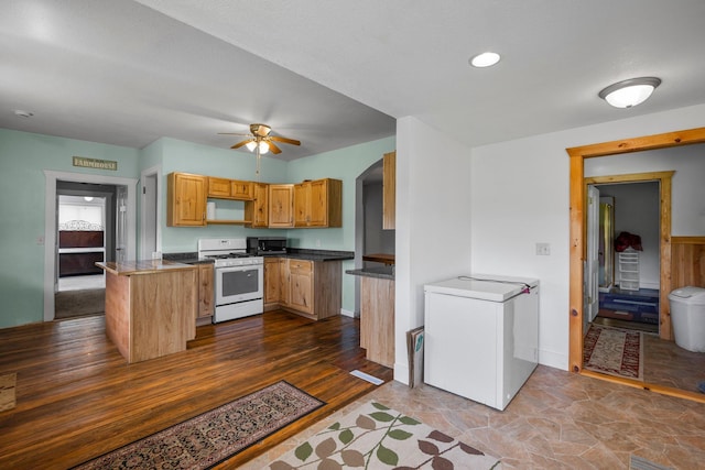 3592 Blom Lake Dr, Frederic, WI 54837 - kitchen with white range with gas cooktop, fridge, stainless steel microwave, arched walkways, and a ceiling fan