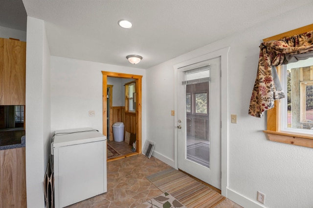 3592 Blom Lake Dr, Frederic, WI 54837 - doorway to outside with baseboards, stone finish flooring, and washer / dryer