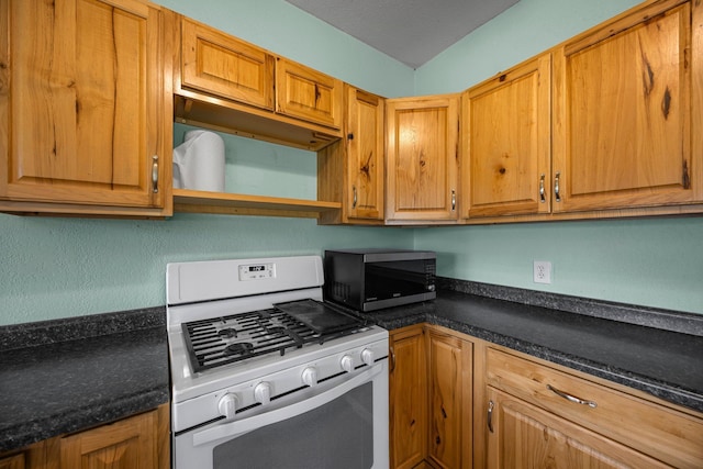 3592 Blom Lake Dr, Frederic, WI 54837 - kitchen with white gas range oven, stainless steel microwave, dark countertops, open shelves, and brown cabinets