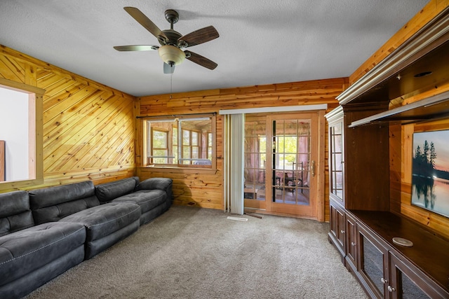 3592 Blom Lake Dr, Frederic, WI 54837 - carpeted living room with healthy amount of natural light, a ceiling fan, wooden walls, and a textured ceiling