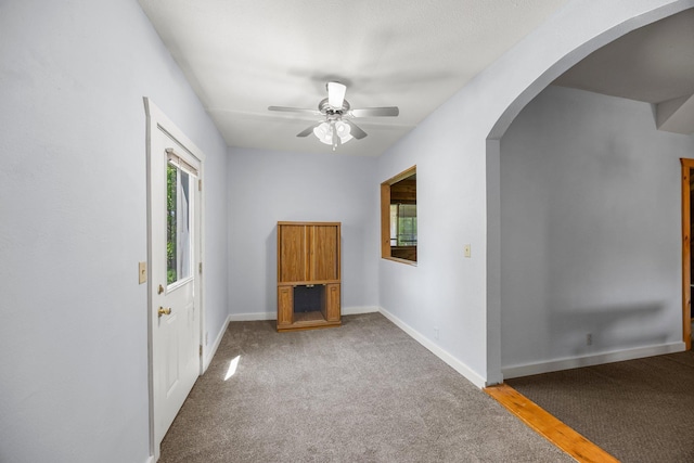 3592 Blom Lake Dr, Frederic, WI 54837 - unfurnished room featuring arched walkways, carpet flooring, a ceiling fan, and baseboards