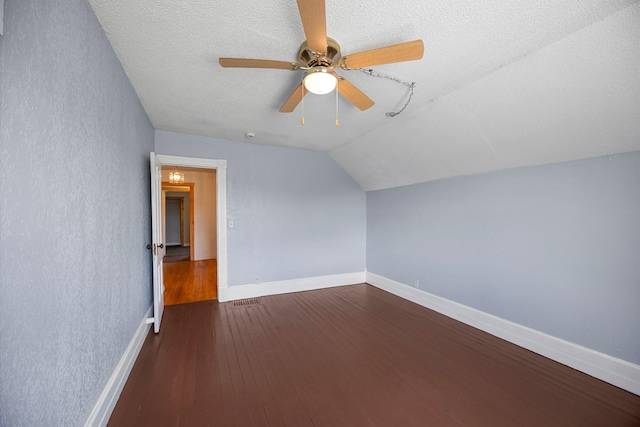 3592 Blom Lake Dr, Frederic, WI 54837 - bonus room featuring dark wood finished floors, a ceiling fan, vaulted ceiling, baseboards, and a textured ceiling