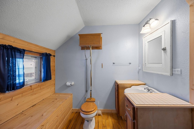 3592 Blom Lake Dr, Frederic, WI 54837 - bathroom with toilet, a textured ceiling, vaulted ceiling, hardwood / wood-style floors, and vanity