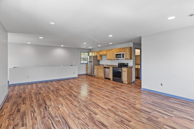 kitchen with stainless steel appliances, open floor plan, wood finished floors, recessed lighting, and baseboards