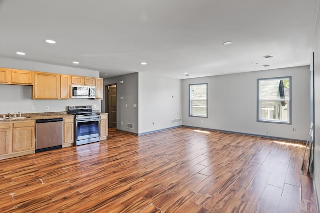kitchen featuring stainless steel appliances, a sink, light brown cabinets, dark wood-style floors, and recessed lighting