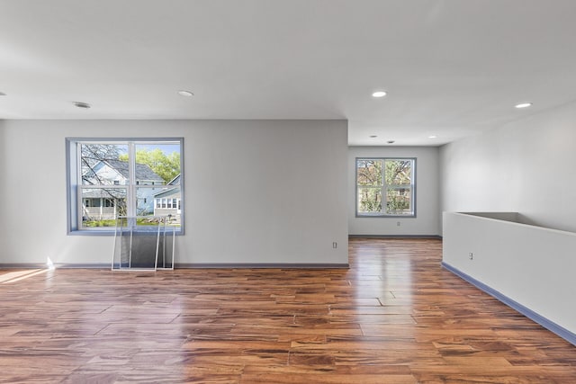 spare room with healthy amount of natural light, wood finished floors, recessed lighting, and baseboards