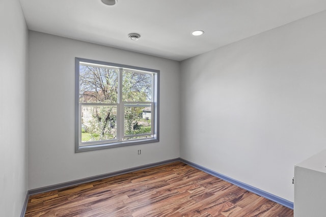 empty room with wood finished floors, recessed lighting, and baseboards