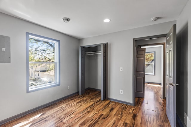 unfurnished bedroom with dark wood-style floors, electric panel, baseboards, a closet, and recessed lighting