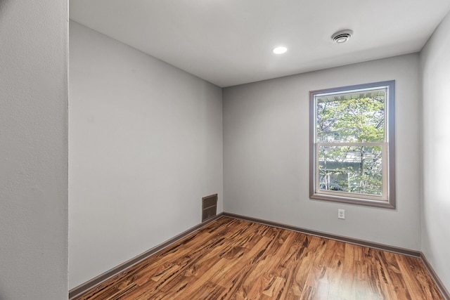 empty room featuring wood finished floors, recessed lighting, and baseboards