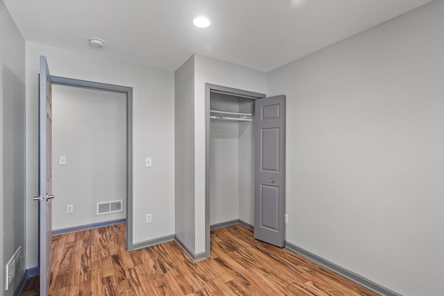 unfurnished bedroom featuring wood finished floors, baseboards, a closet, and recessed lighting
