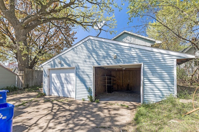 detached garage featuring asphalt driveway and fence