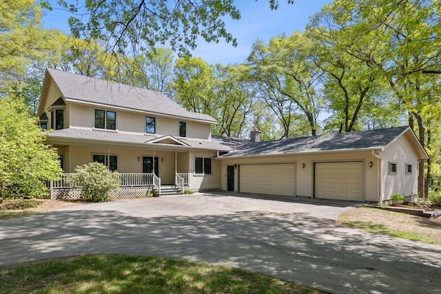 view of front of home with asphalt driveway, covered porch, and an attached garage