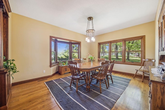 dining room with baseboards, light wood-style flooring, and a chandelier