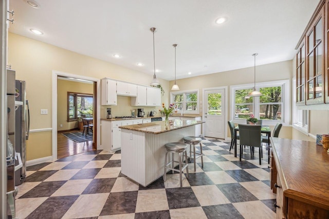 kitchen featuring a kitchen island, white cabinets, recessed lighting, a breakfast bar, and baseboards