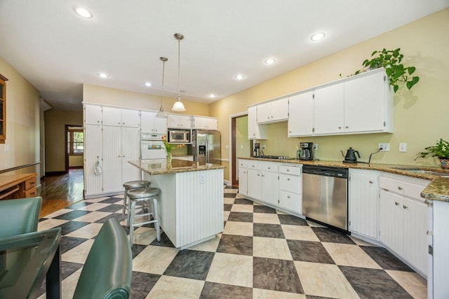 kitchen featuring appliances with stainless steel finishes, white cabinets, recessed lighting, dark stone counters, and a sink