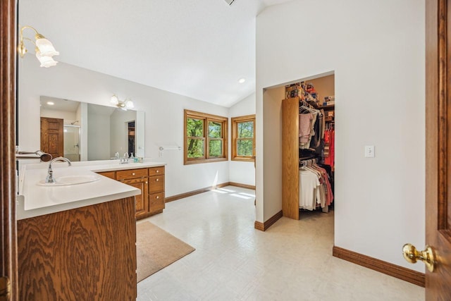 full bath with a shower stall, lofted ceiling, baseboards, tile patterned floors, and two vanities