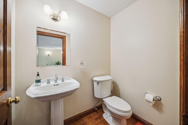 bathroom with wood finished floors, toilet, and baseboards
