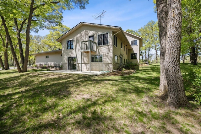 back of property featuring a balcony, a patio area, and a yard