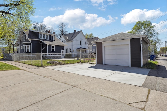 view of front of house with a detached garage, driveway, an outdoor structure, and fence
