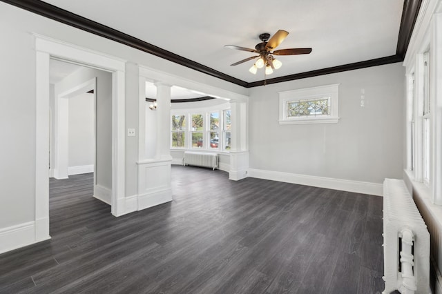 empty room featuring radiator heating unit, crown molding, decorative columns, ceiling fan, and dark wood finished floors