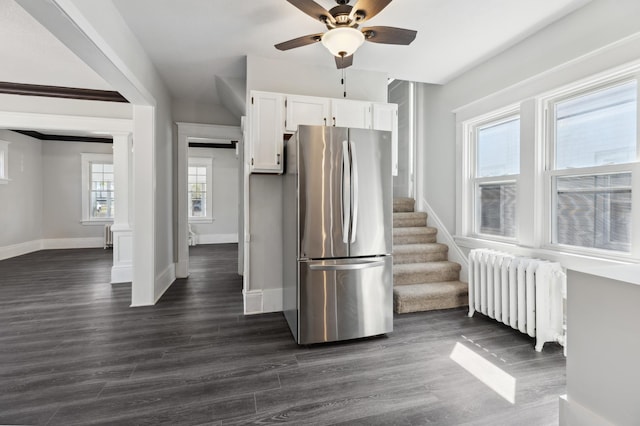 kitchen featuring radiator heating unit, freestanding refrigerator, white cabinets, ceiling fan, and baseboards
